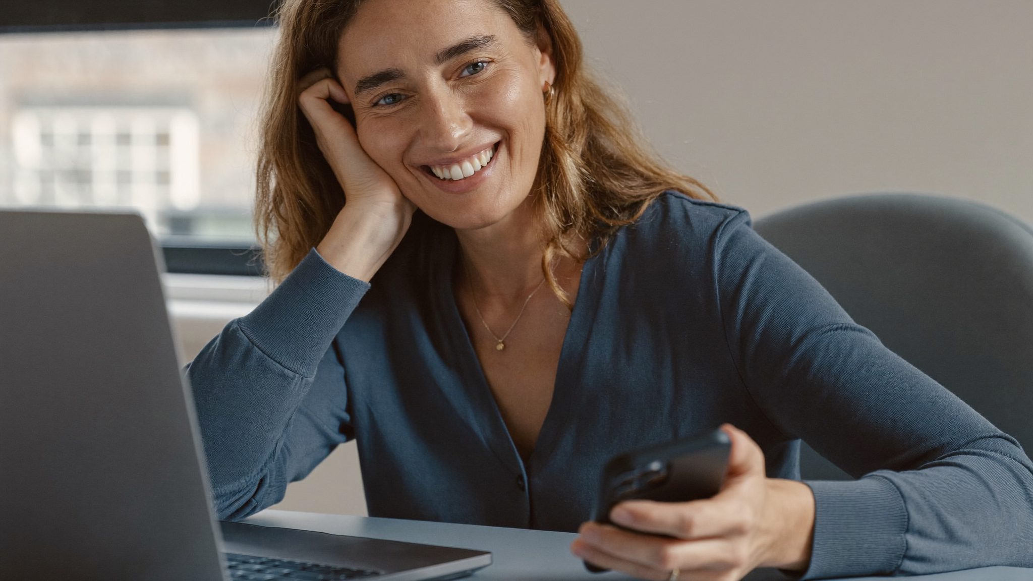 Une femme d'une cinquantaine d'années au téléphone devant son ordinateur portable